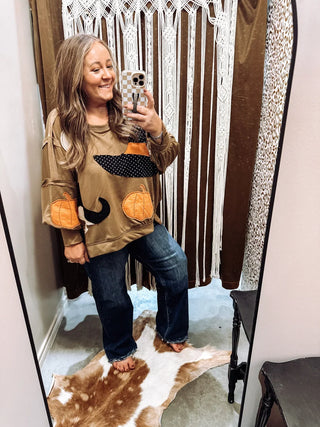 Brittani wearing a Halloween pumpkin patch sweatshirt and wide leg jeans