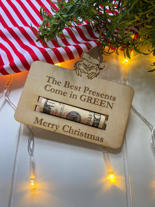 Wooden Christmas money holder with a rolled bill on a red and white striped cloth