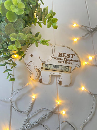 Wooden elephant money holder with a rolled bill tucked into the slot, styled with greenery