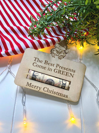 Laser engraved wooden money holder that says The Best Presents Come in Green with a rolled bill