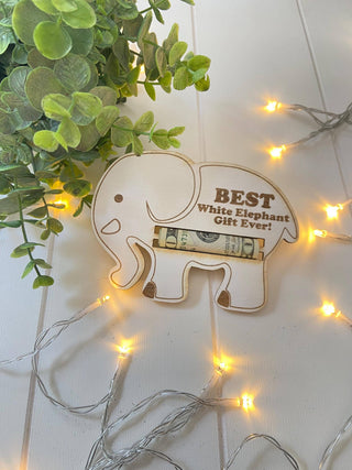 Wooden elephant money holder with a rolled bill, greenery and warm string lights