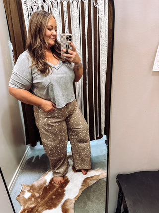Grey washed boxy V-neck pocket tee with side slits and folded raw edge sleeves, side view with fawn print pants