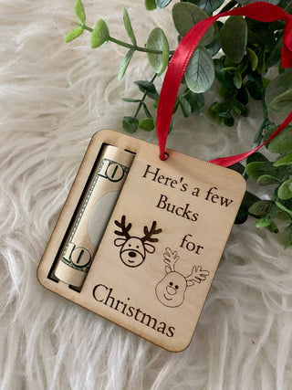 Wooden reindeer money holder ornament with a rolled bill, red ribbon and greenery