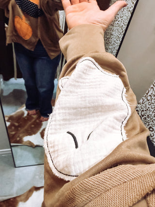 Close up of orange gauze pumpkin appliqué with black contrast stitching on sweatshirt sleeve, photo 4