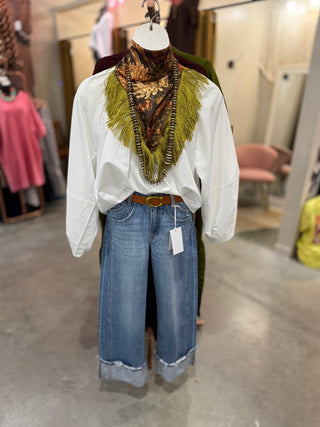 Peacock print fringed scarf worn as a wild rag with a white blouse and wide leg jeans