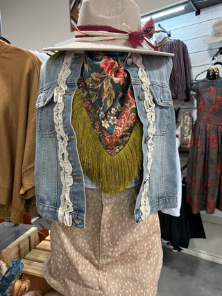 Peacock print fringed scarf worn as a wild rag with a distressed denim vest and fawn print skirt