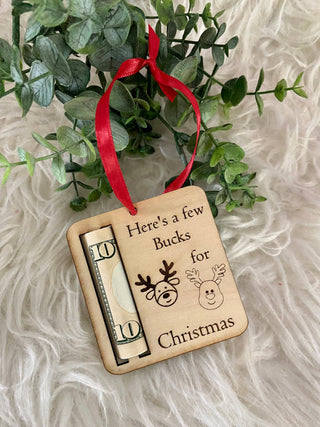 Christmas money holder ornament with a rolled bill hanging from a red ribbon
