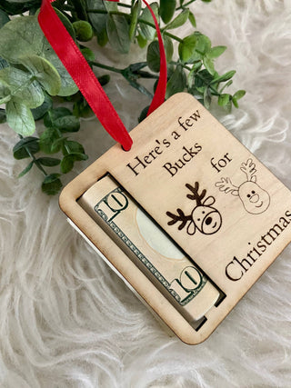 Angled view of the wooden Bucks for Christmas money holder ornament with a rolled bill