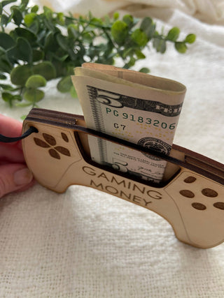 Hand holding the wooden Gaming Money controller showing a bill in the slot