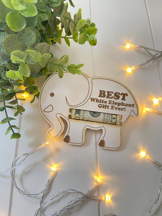 Laser engraved wooden elephant money holder with a rolled bill in the slot and warm string lights